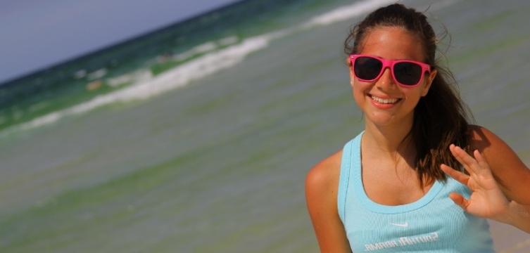 Student in sunglasses smiling on the beach.
